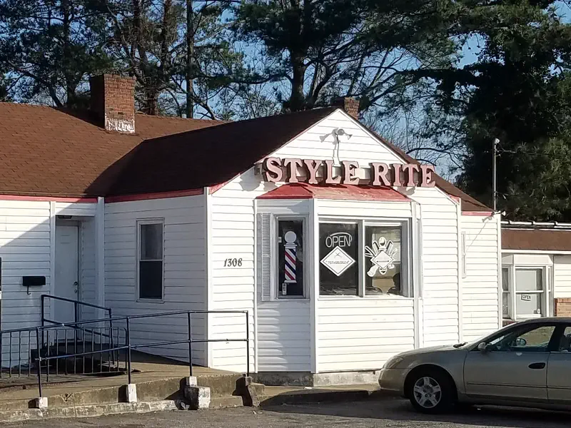 Style Rite from the parking lot: a white clapboard house with STYLE RITE on the gable and a barber pole in the bay window