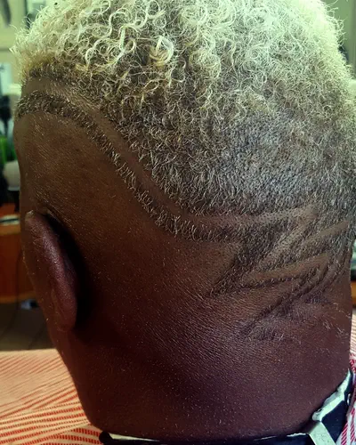 Bleached curls over a fade with a line design, from behind