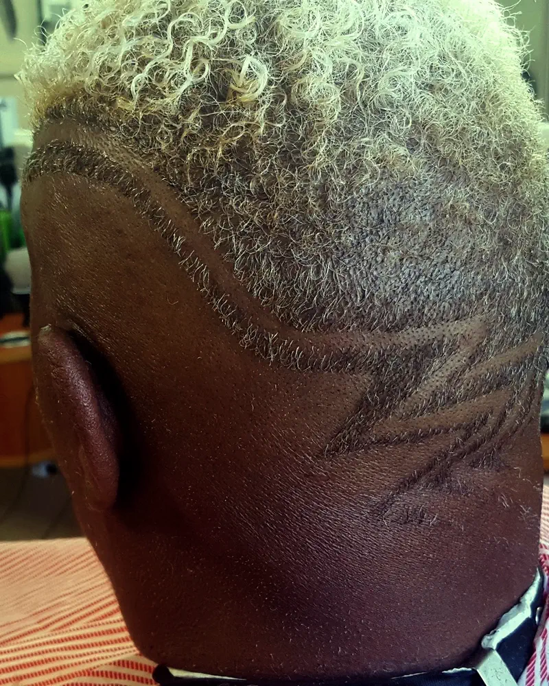 Bleached curls over a fade with a line design, from behind